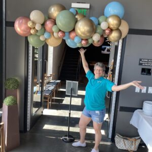 Dorothy of Festive Balloons standing next to a custom Freeform Garland balloon decor
